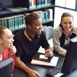 A boy and two girls sitting in front of the computer