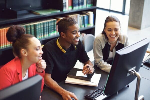 A boy and two girls sitting in front of the computer